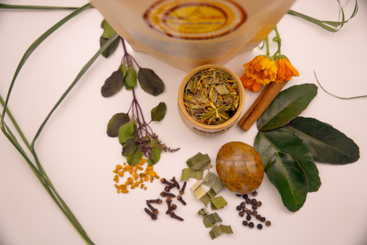 Golden Healer Tea package surrounded by tulsi, turmeric, Golden Healer Crystal, Makrut lime leaf and other herbs.