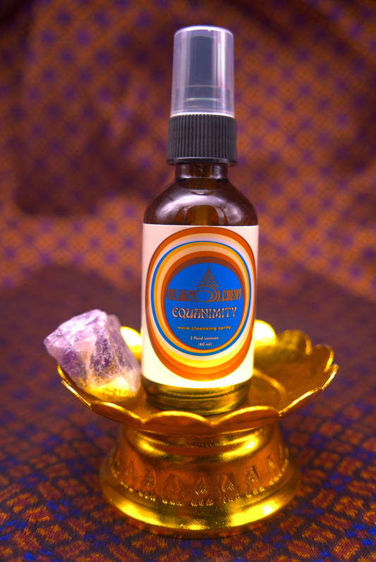 Bottle of Equanimity Aura Spray with Amethyst crystal  on a decorative stand against a Khmer silk fabric.
