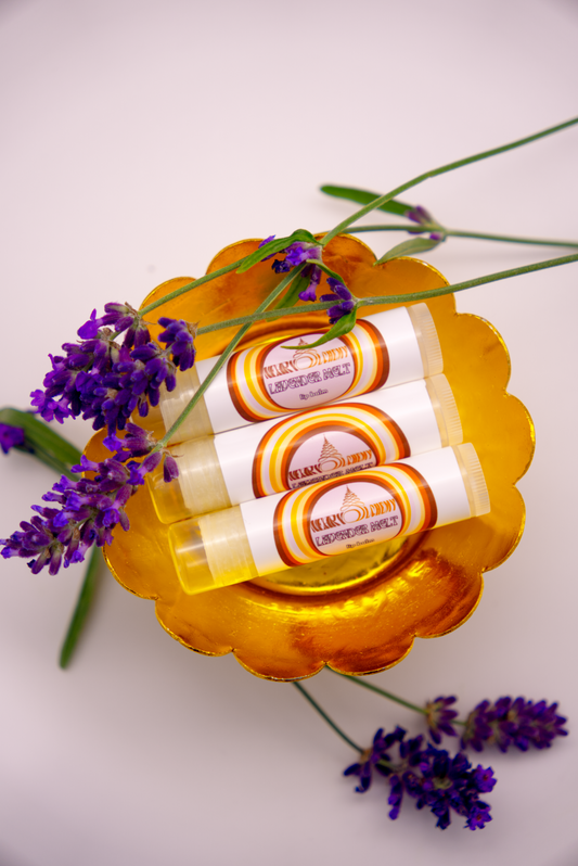 Three Lavender Melt lip balms in a decorative holder with lavender flowers on a light background