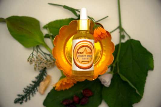 Bottle of Sunset Aura Facial Oil on decorative stand surrounded by herbs and Sunset Aura crystal.
